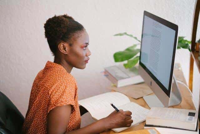 Woman studying at desk with book and computer