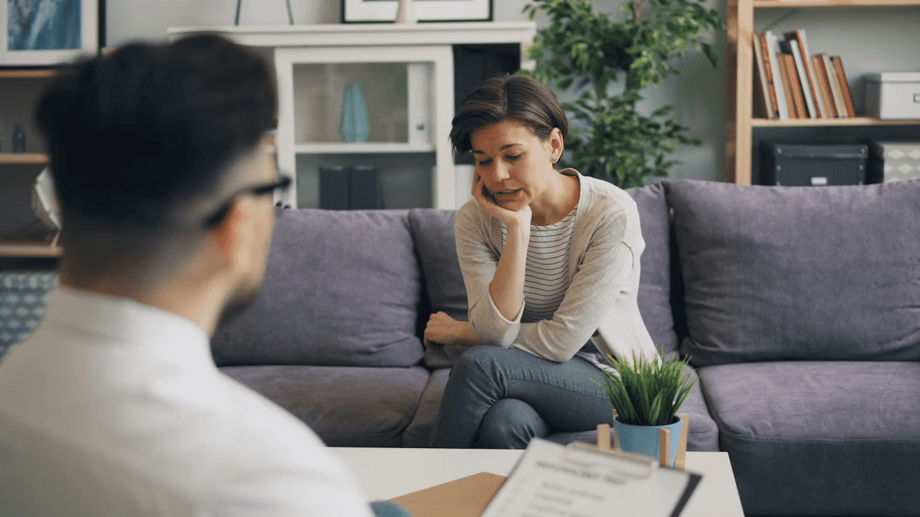 Woman on couch talking to man in a counselling session